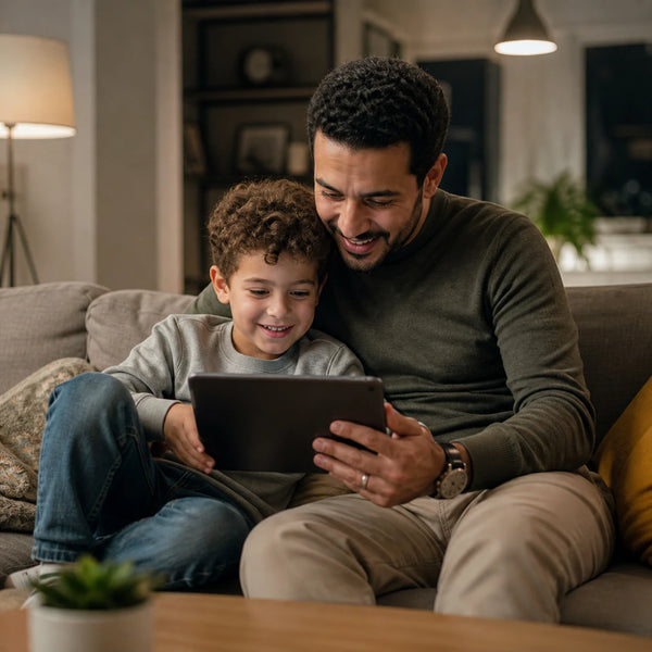 Father and son looking at a tablet together on the sofa